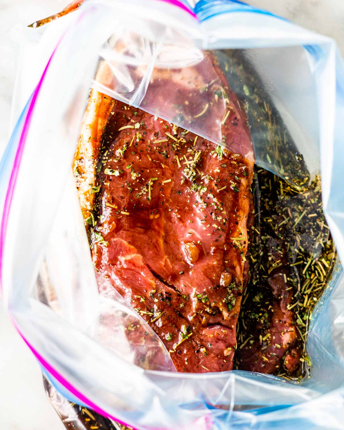 overhead shot of steaks in marinade in an open ziploc bag
