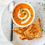 tomato bisque in a soup bowl with a grilled cheese sandwich