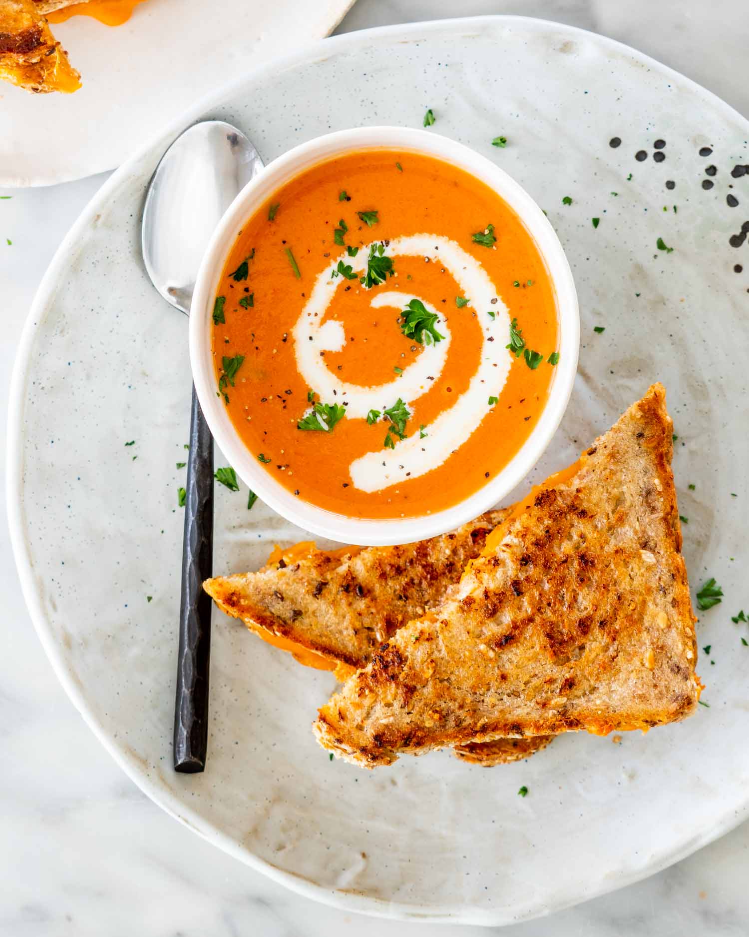 tomato bisque in a soup bowl with a grilled cheese sandwich