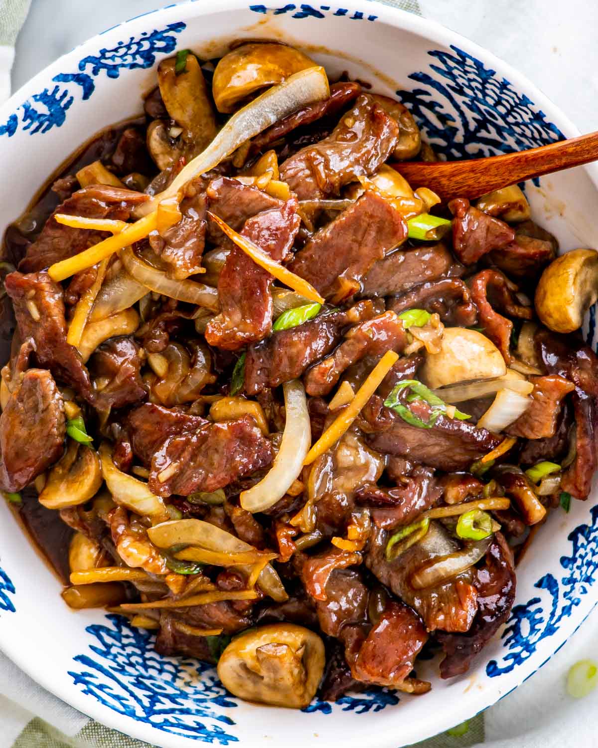 overhead shot of beef mushroom stir fry in a white and blue bowl