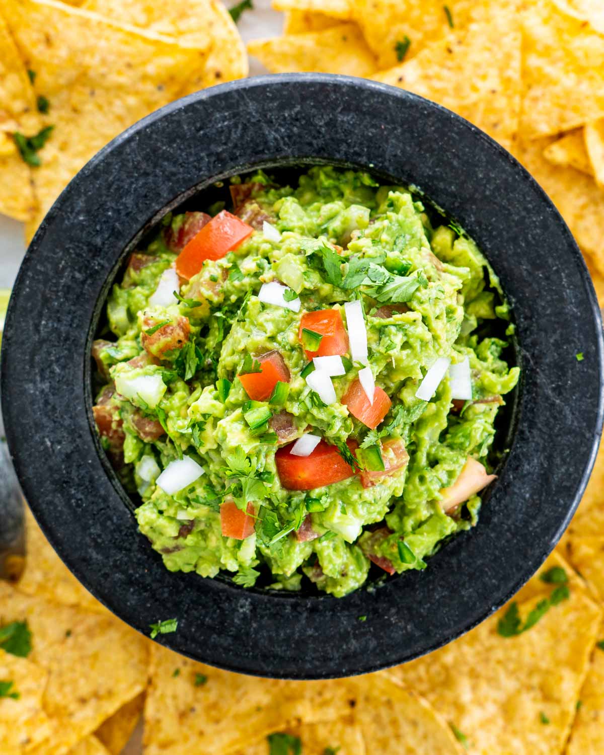 overhead shot of guacamole in a bowl surrounded by tortilla chips