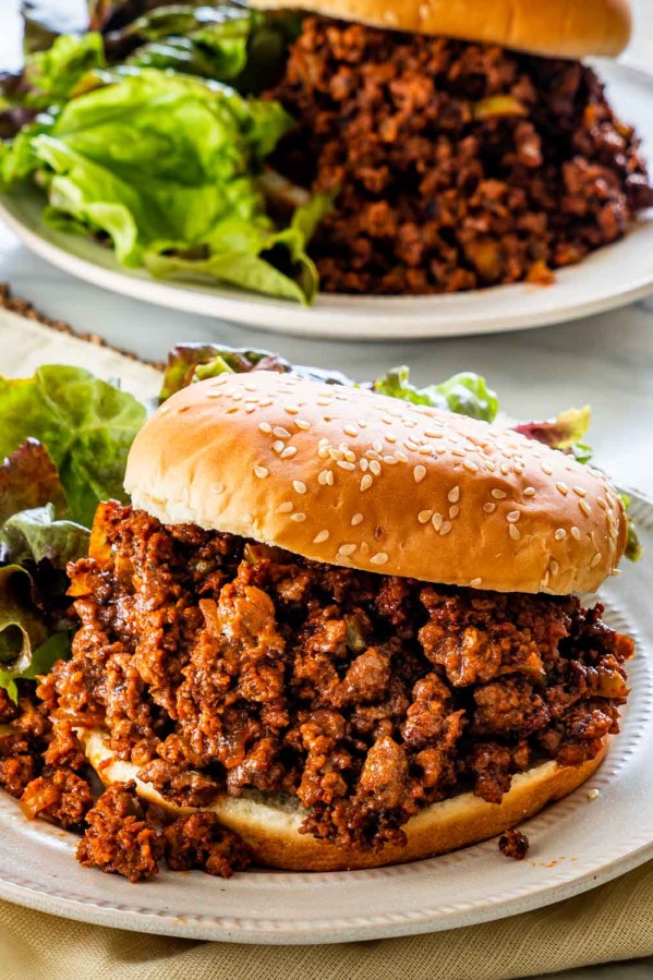 two plate with sloppy joes and buns next to a greens salad