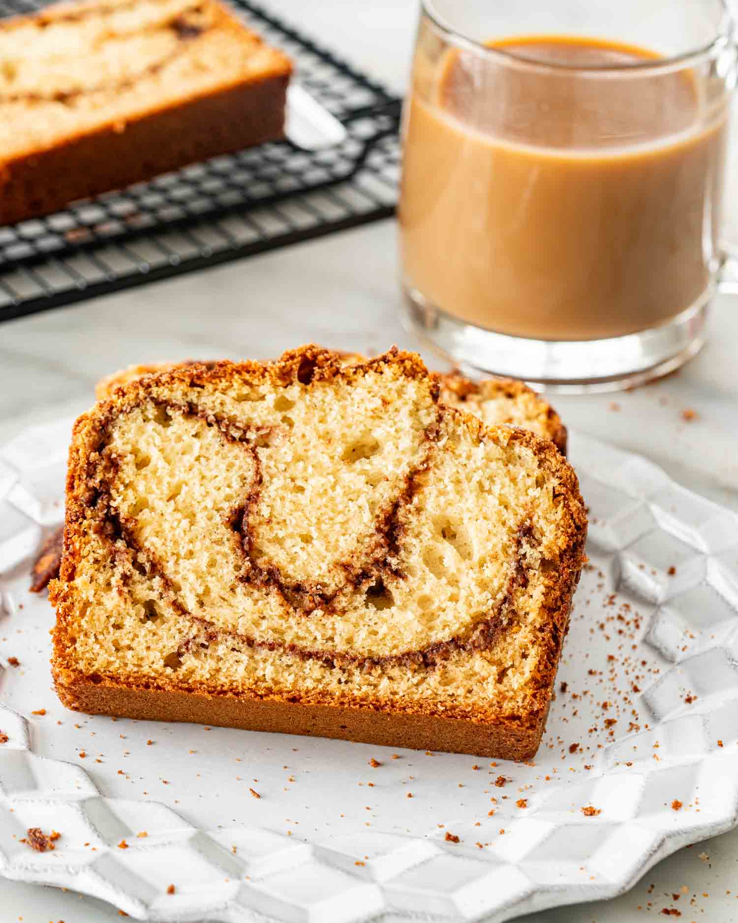 two slices of coffee cake bread on a white plate with a cup of coffee.
