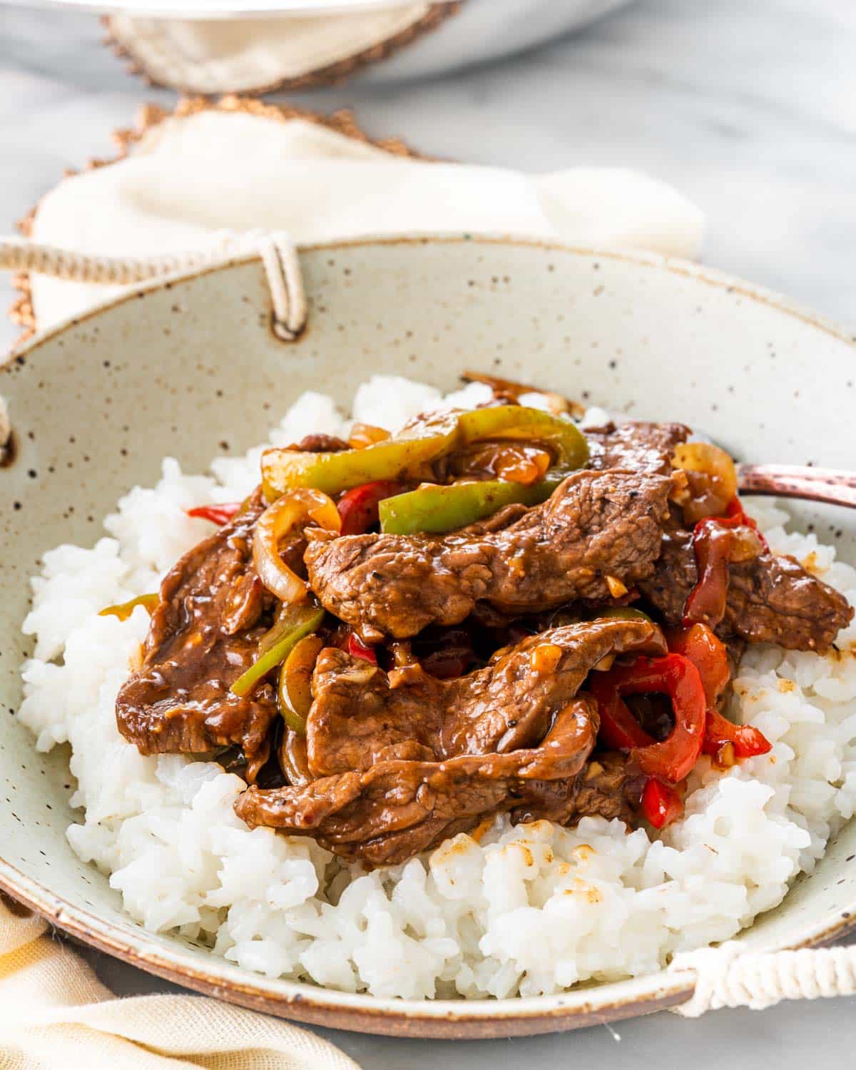 pepper steak over a bed of rice in a bowl
