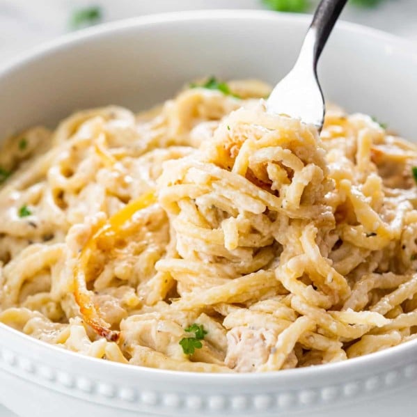 a fork twirling noodles in a bowl full of turkey tetrazzini.