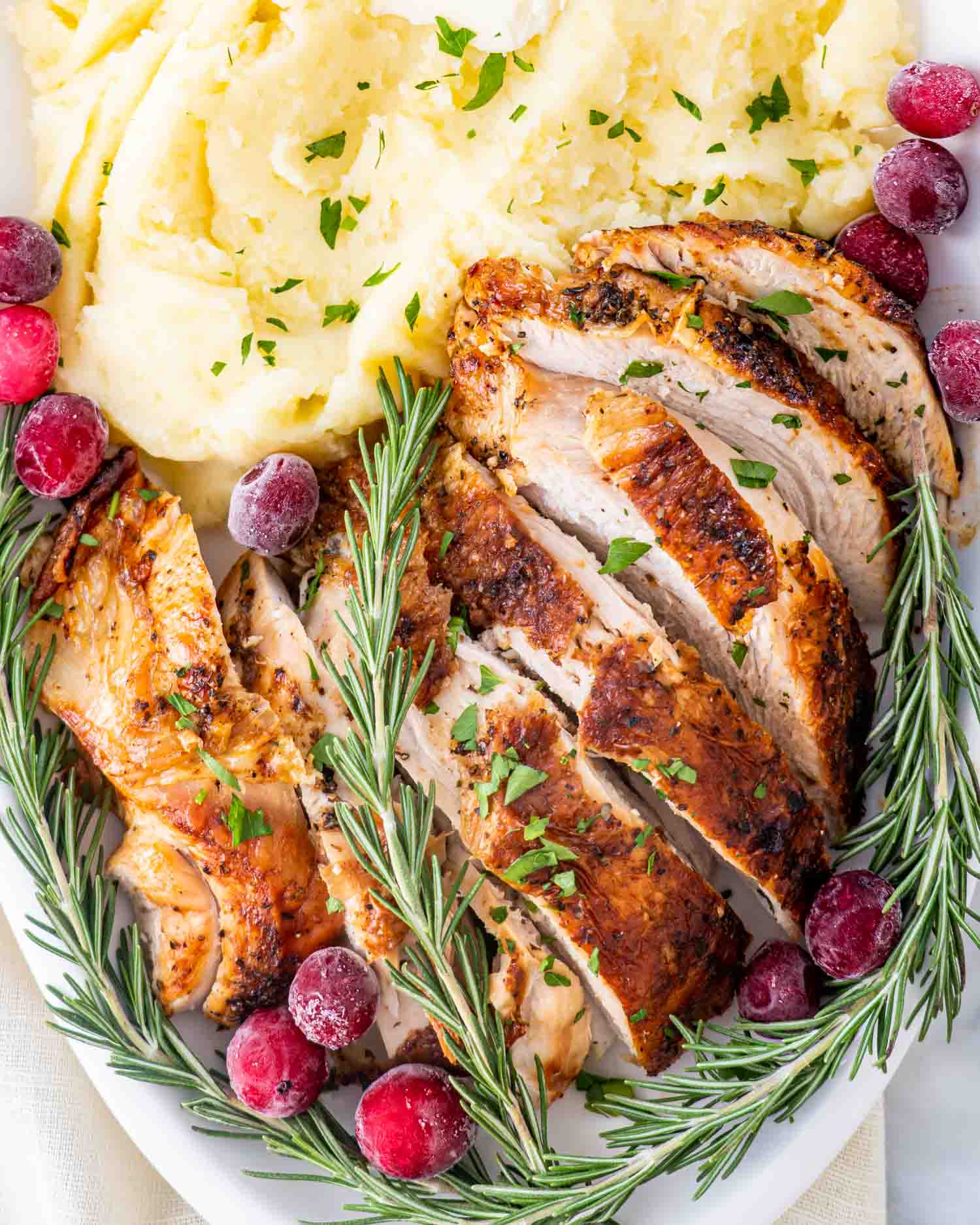 air fryer turkey breast on a white platter with mashed potatoes.