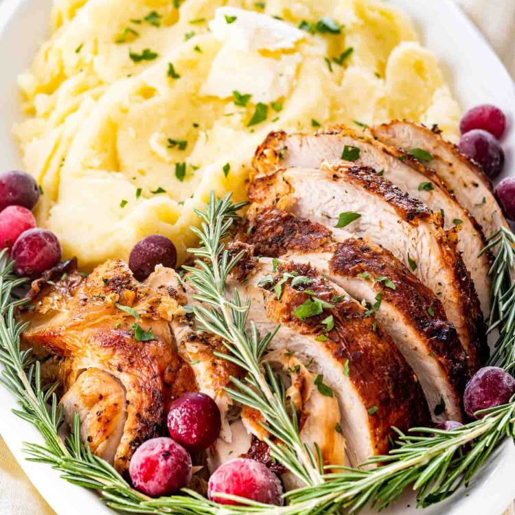 air fryer turkey breast on a white platter with mashed potatoes.
