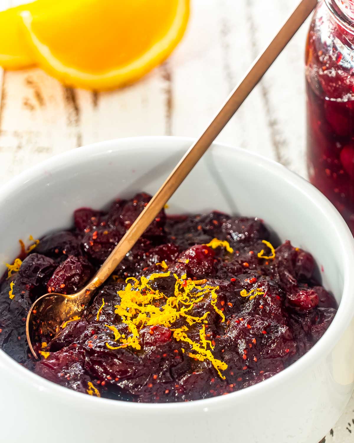 cranberry sauce in a white bowl with a spoon inside.