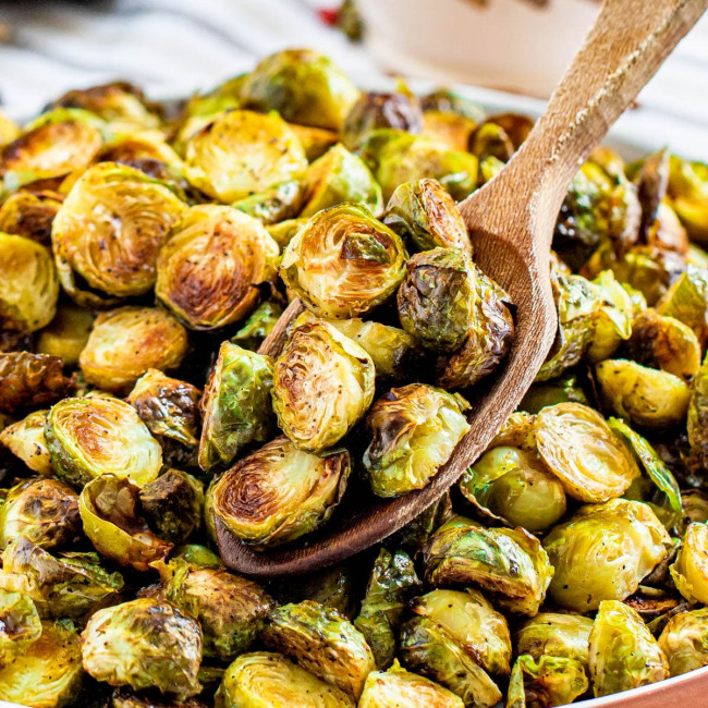 roasted burssels sprouts on a plate with a wooden spoon holding some.