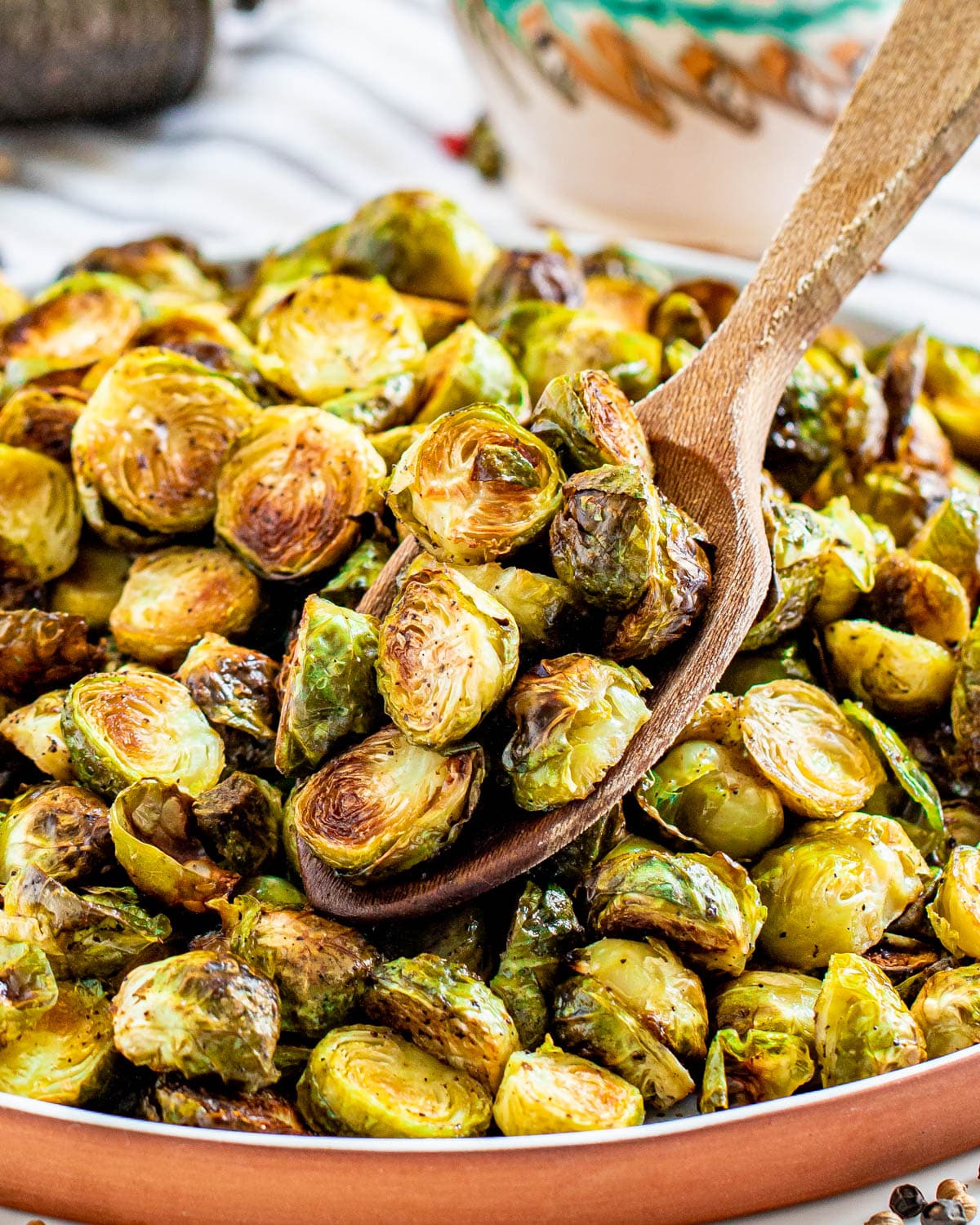 roasted burssels sprouts on a plate with a wooden spoon holding some.