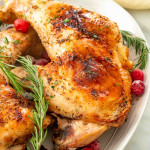 2 turkey legs on a platter garnished with cranberries and rosemary.