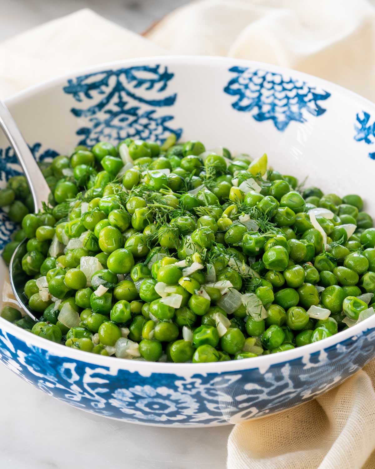 sautéed peas in a bowl with a fork inside.