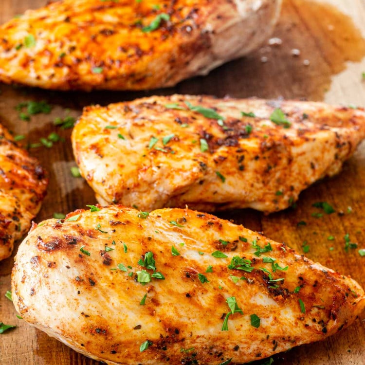 3 cooked chicken breasts on a cutting board.