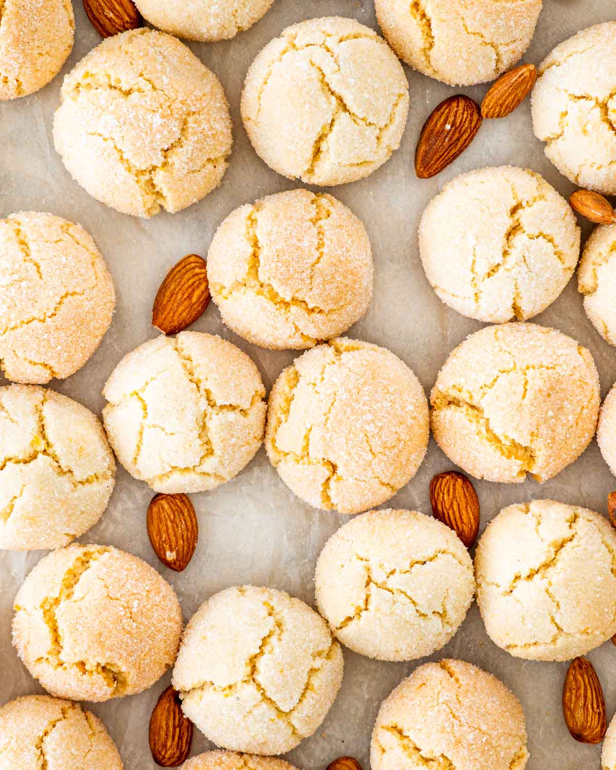overhead shot of amaretti cookies on parchment paper with almonds around.