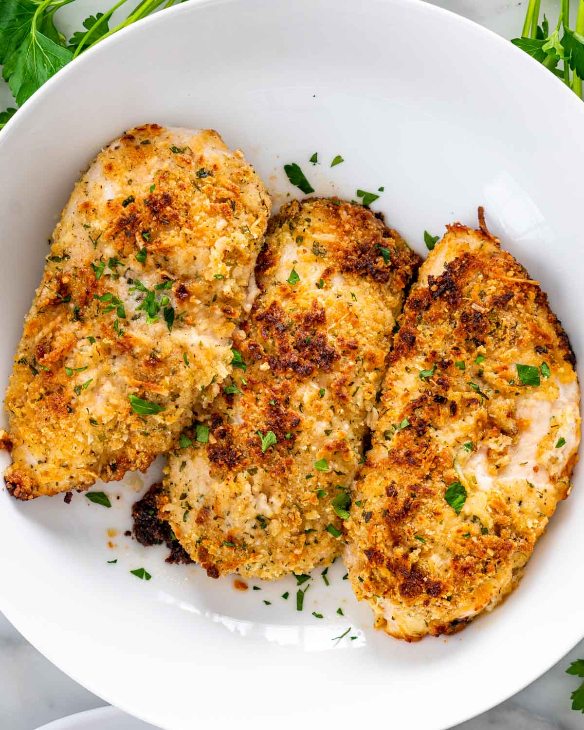overhead shot of 3 baked chicken breasts in a round bowl.