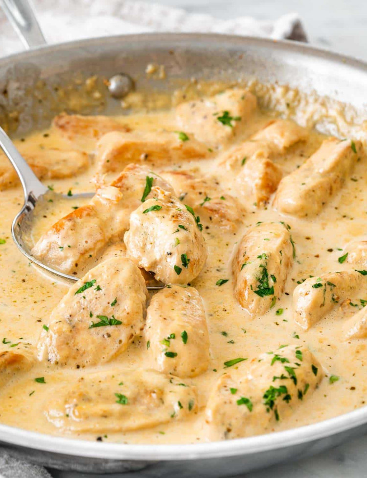 creamy chicken lazone in a skillet garnished with parsley.
