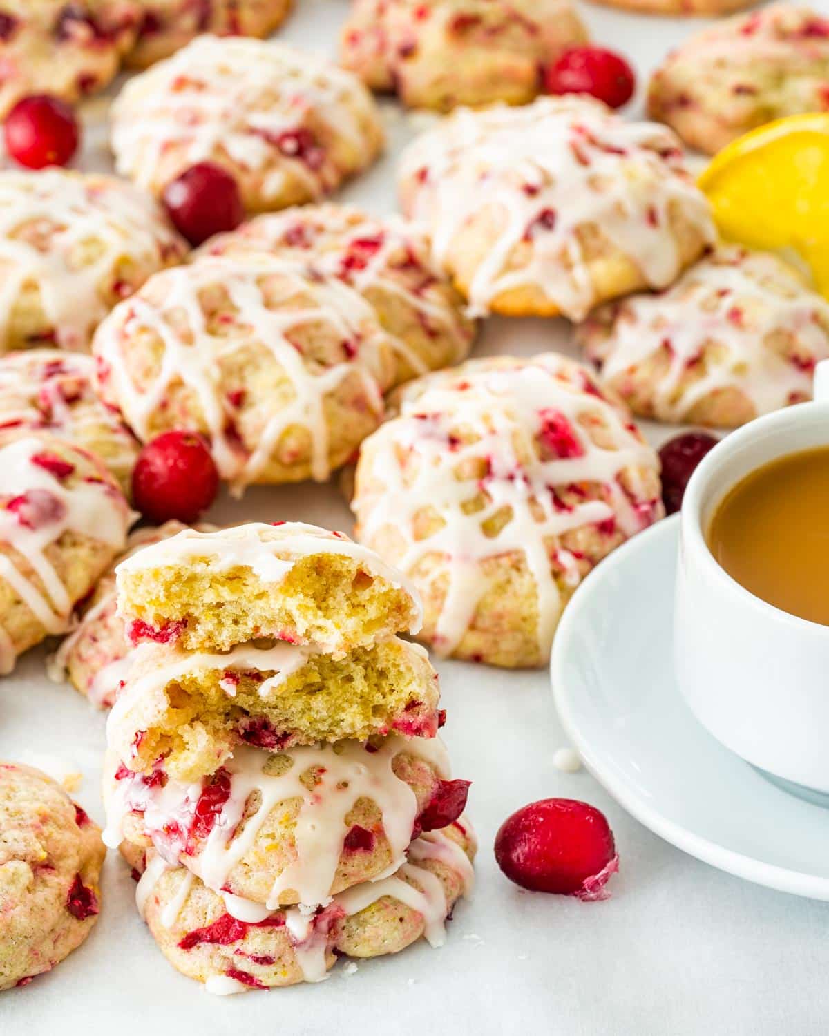 a bunch of cranberry orange cookies stacked next to a cup of coffee.