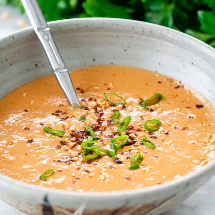 peanut sauce in a bowl garnished with crushed peanuts and red pepper flakes.