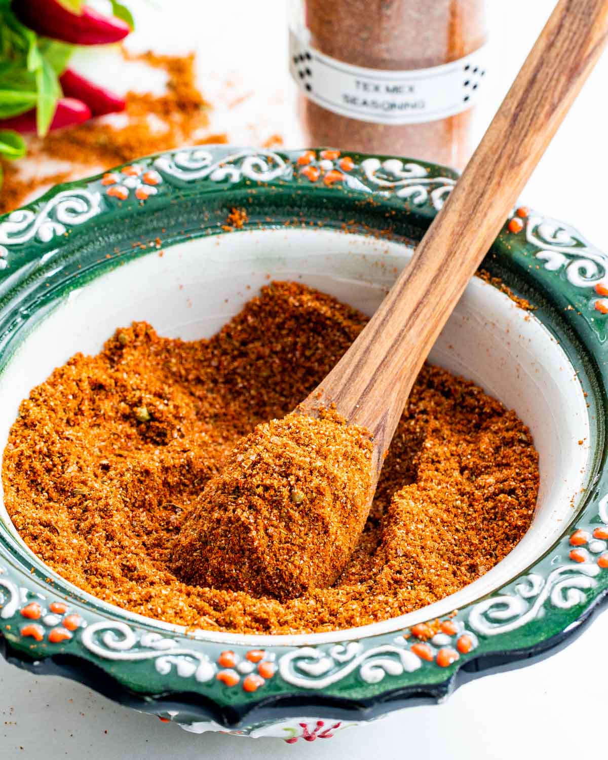 homemade tex mex seasoning in a bowl with a tiny wooden spoon inside.