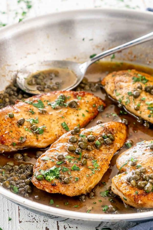 chicken piccata in a skillet garnished with parsley.