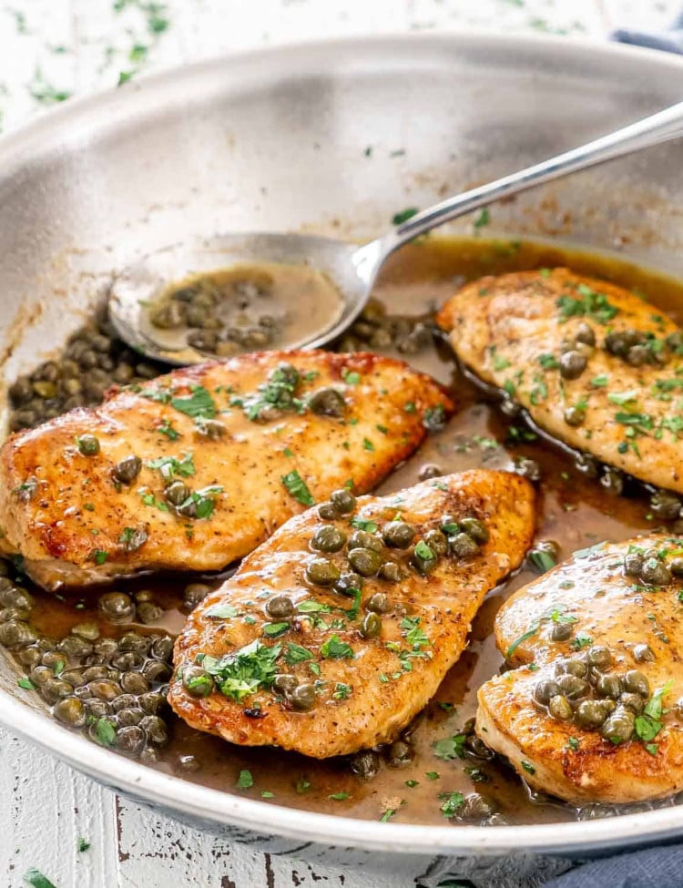 chicken piccata in a skillet garnished with parsley.