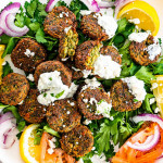 overhead of falafel on a plate with tzatziki, feta, tomatoes and onions.