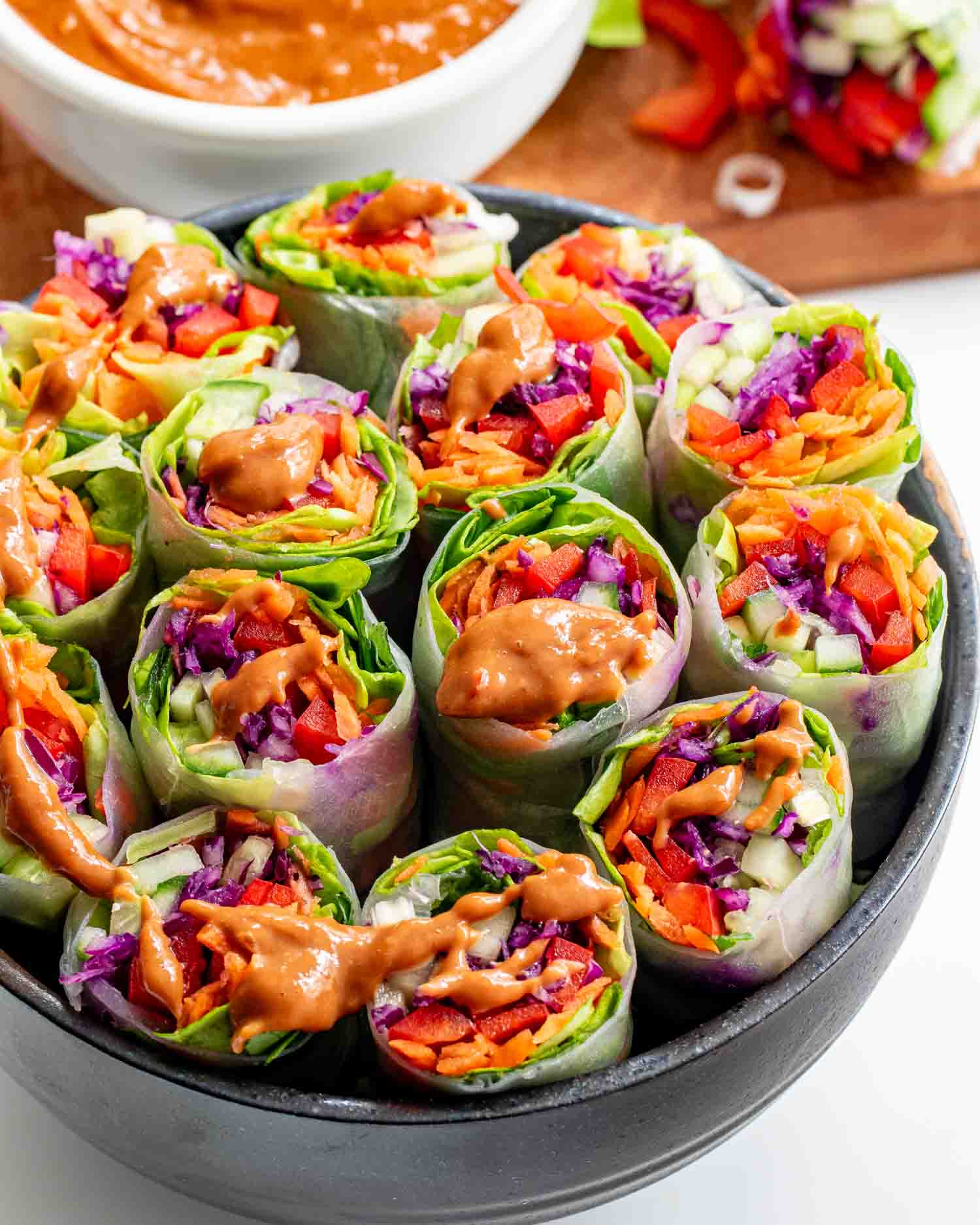 spring rolls cut in half in a black bowl with peanut sauce.