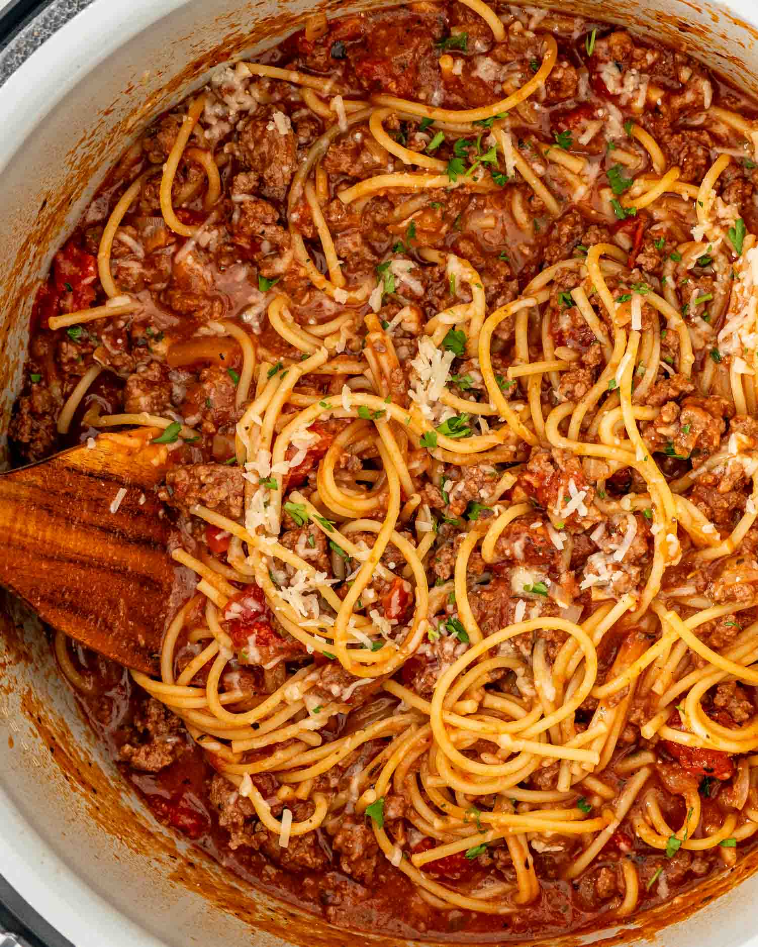 closeup of spaghetti in an instant pot with a wooden spoon inside.