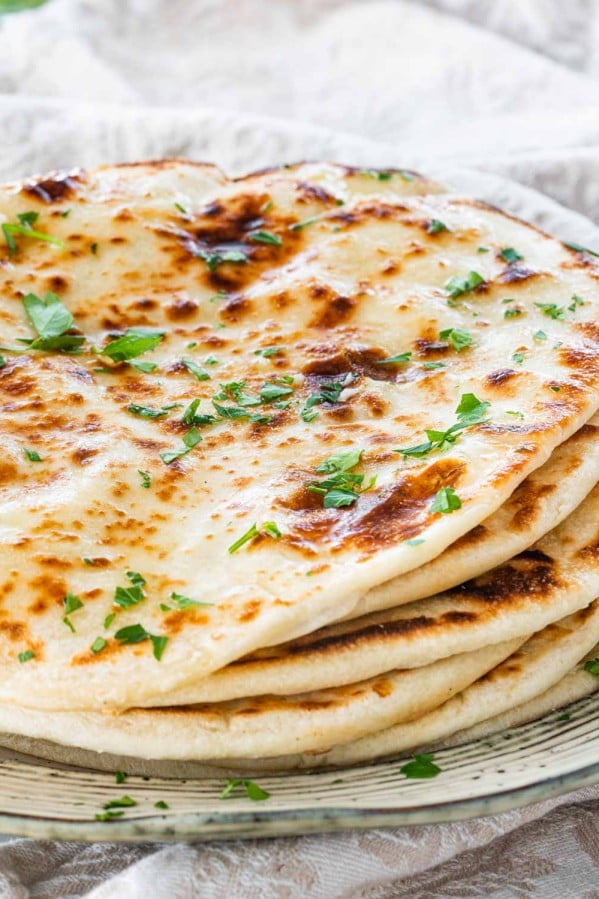 a plate with a pile of flatbreads brushed with garlic butter.