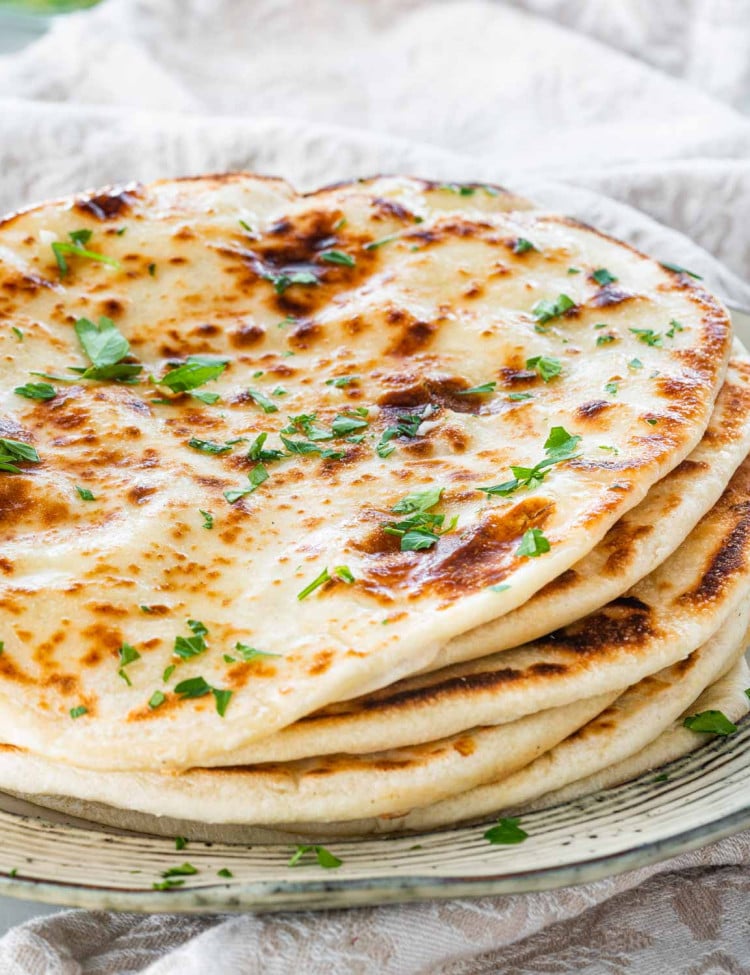 a plate with a pile of flatbreads brushed with garlic butter.