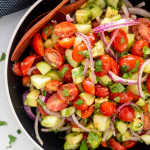 closeup of avocado salad in a black bowl.