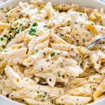 closeup of italian mac and cheese in a white bowl with a big serving spoon.