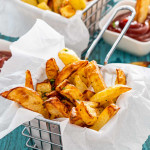 french fries in a basket with a small bowl with ketchup.