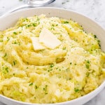 a big white bowl full of colcannon topped with butter.