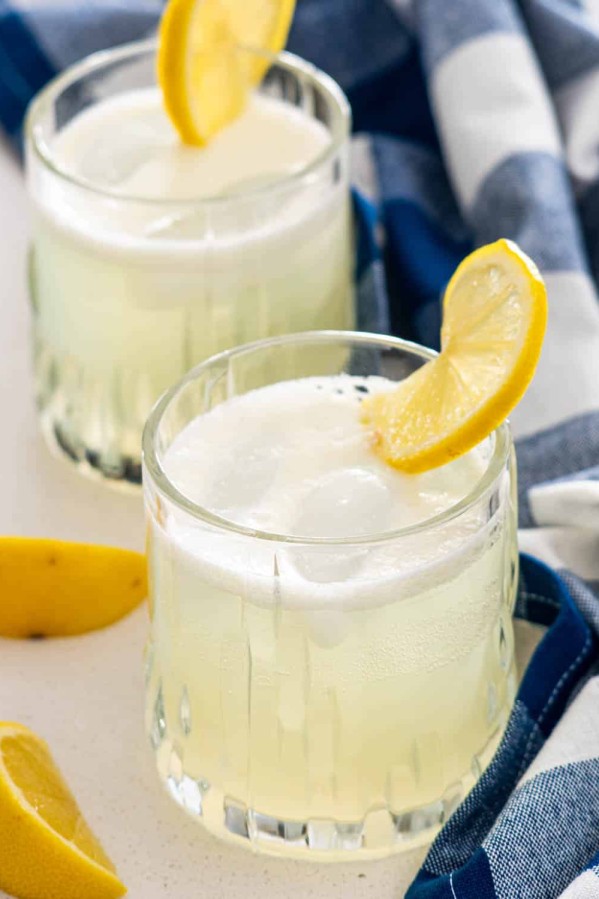 two glasses with gin fizz and garnished with lemon slice.