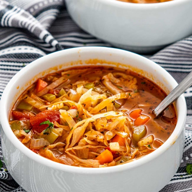 cabbage soup in a white bowl with a spoon inside.