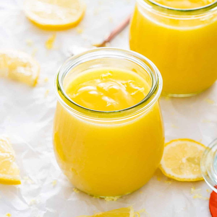 lemon curd in little jars with lemon slices around.