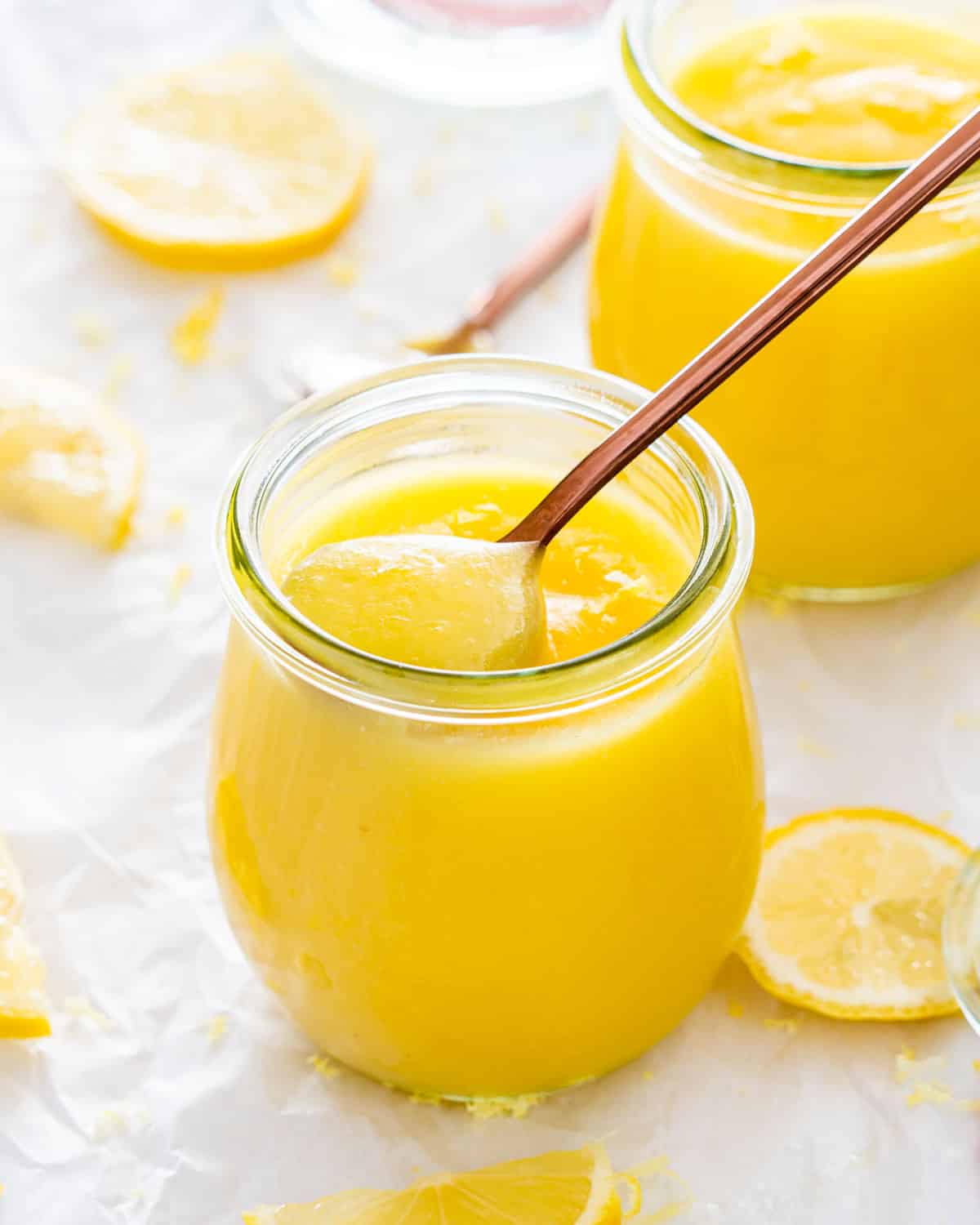 lemon curd in little jars with a spoon inside.