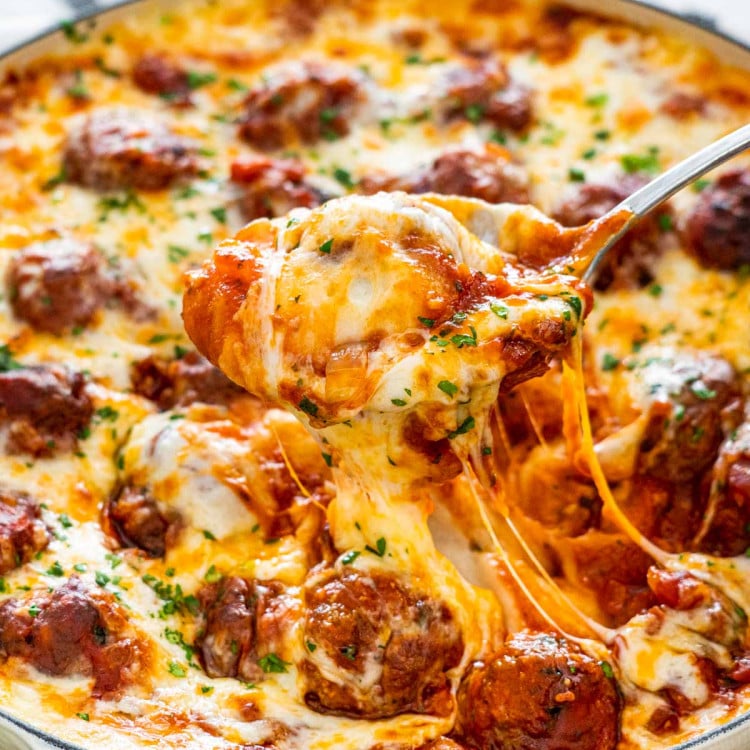 a serving spoon lifting up some meatball mashed potato casserole from a braiser.