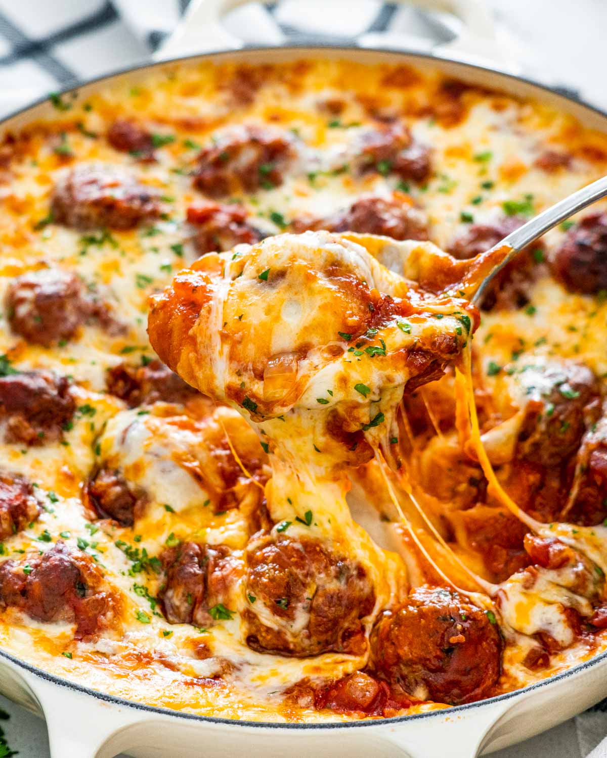 a serving spoon lifting up some meatball mashed potato casserole from a braiser.