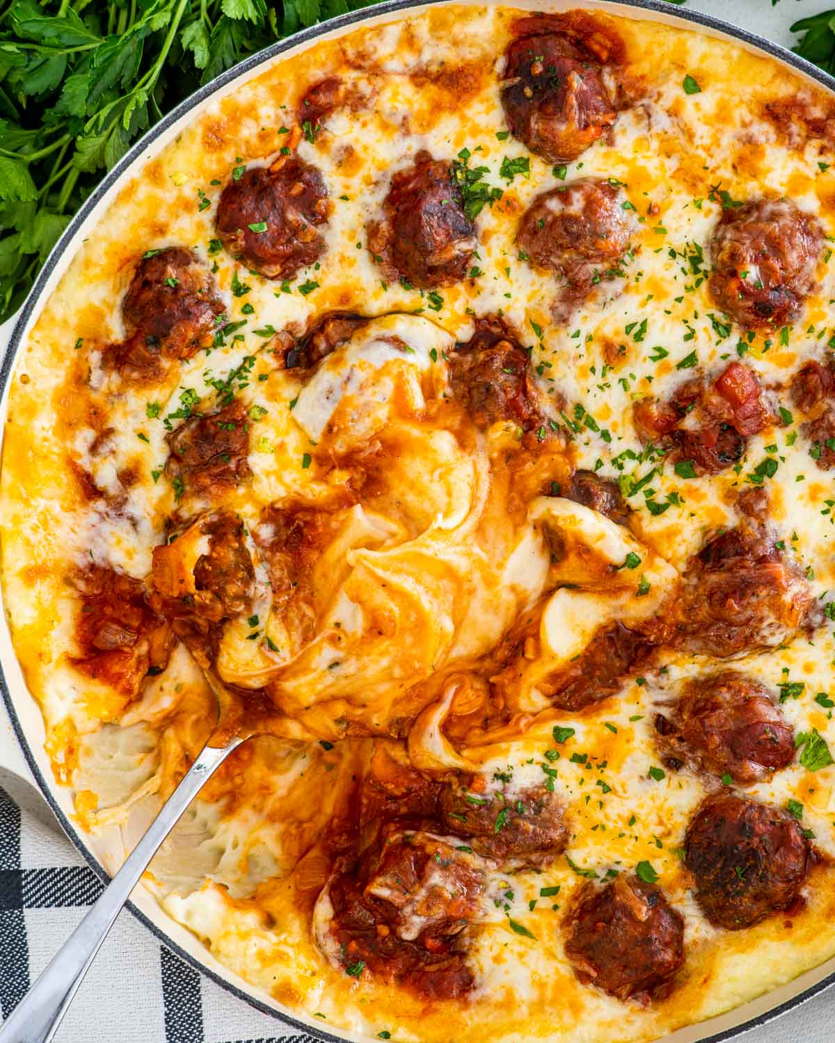 meatball mashed potato casserole in a braiser with a serving spoon inside.