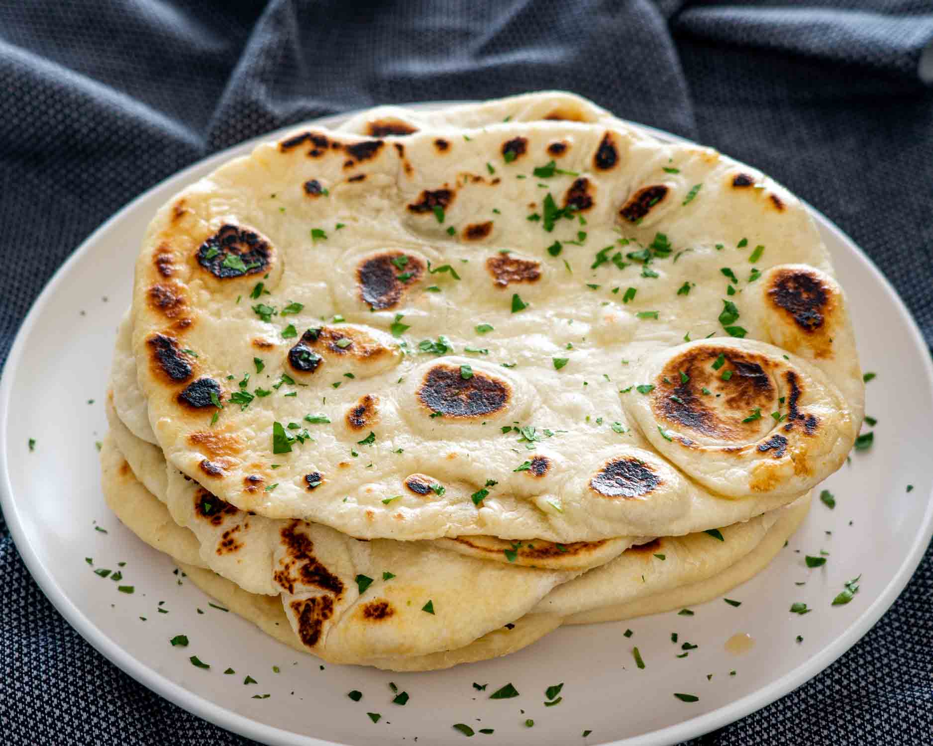 a stack of naan bread on a plate garnished with parsley.