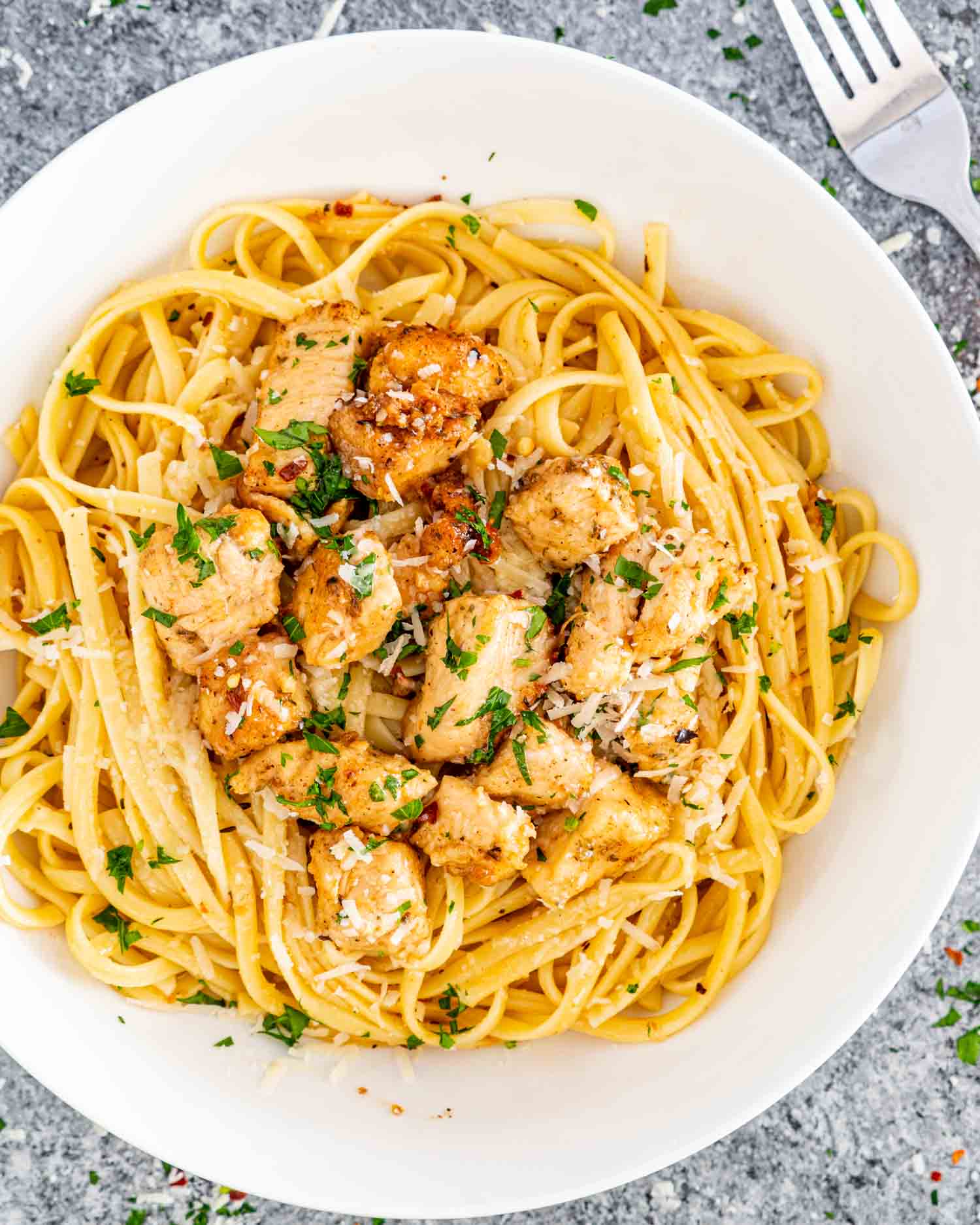 chicken scampi with linguini in a white bowl.