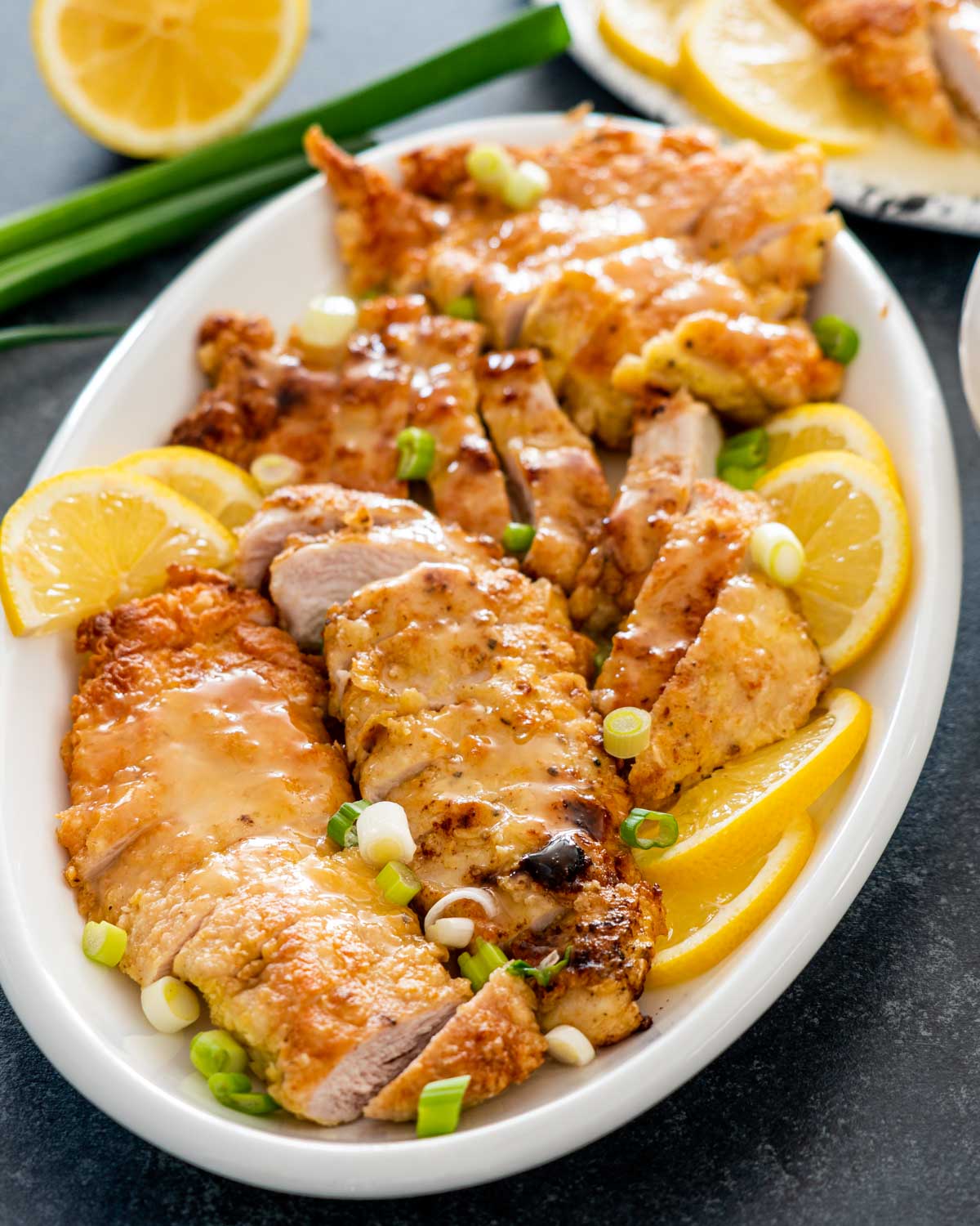chinese lemon chicken on a serving platter garnished with green onions.