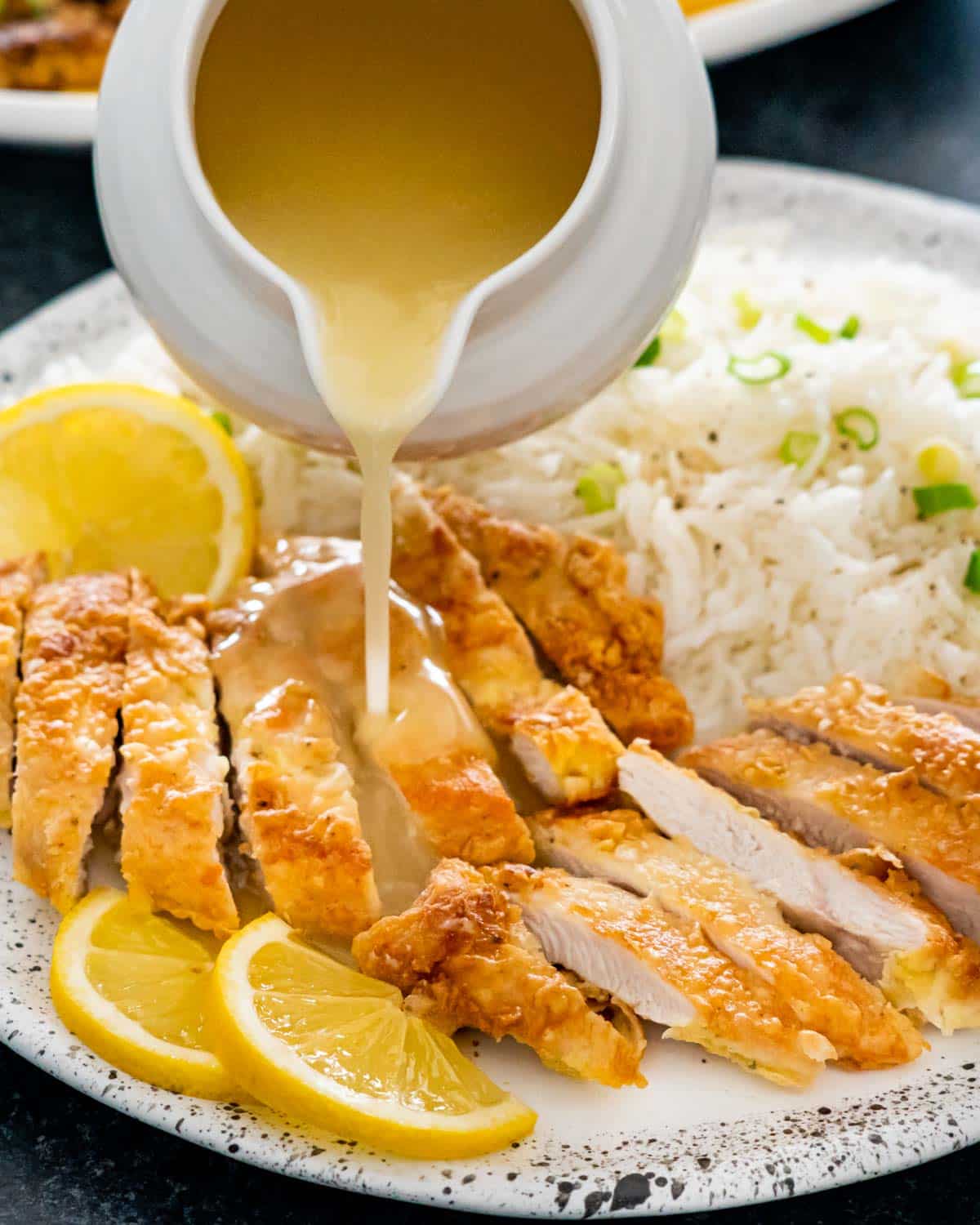 pouring lemon sauce over fried chicken.