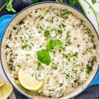 cilantro lime rice in a pot garnished with cilantro and lime wedge.