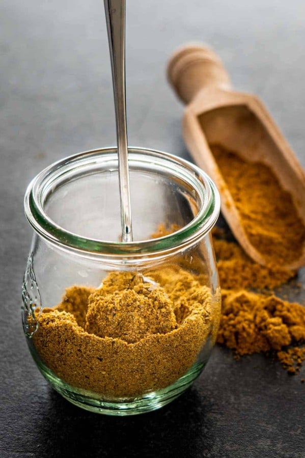 curry powder in a tulip jar with a spoon inside.