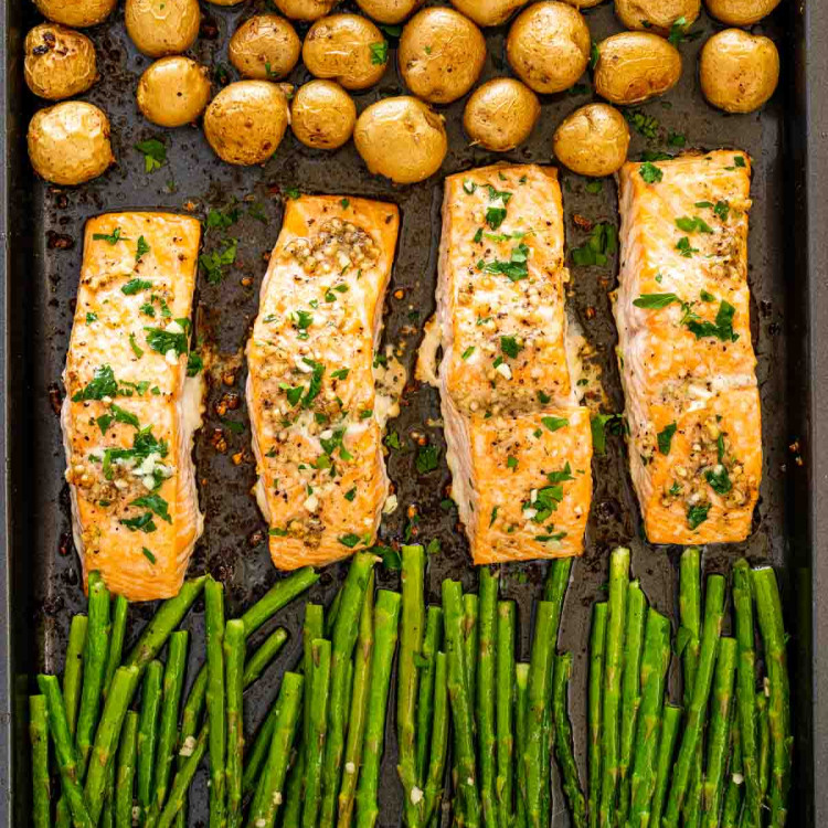 garlic butter salmon with asparagus and baby potatoes on a sheet pan.
