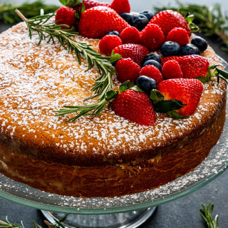olive oil cake on a cake platter garnished with berries.