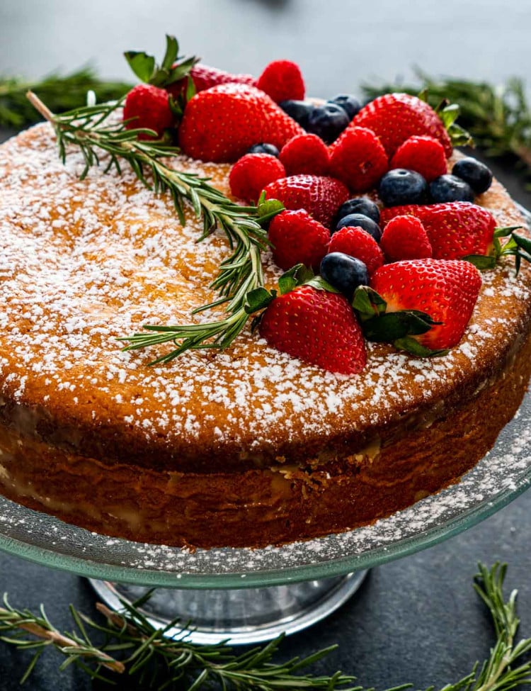 olive oil cake on a cake platter garnished with berries.